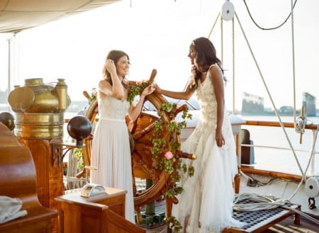 Two brides stdning by wheel on the Tall Ship Elissa