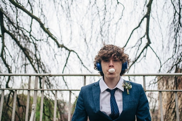 Young groomsman blowing bubblegum bubble