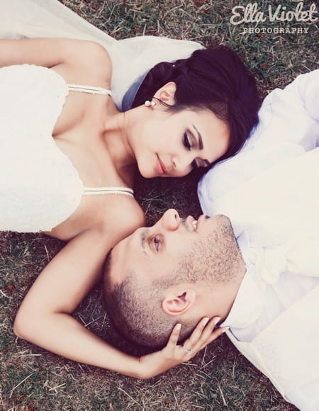 Bride and groom laying on ground looking at each other - Picture by Ella Violet Photography