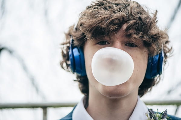 Young groomsman blowing bubblegum bubble