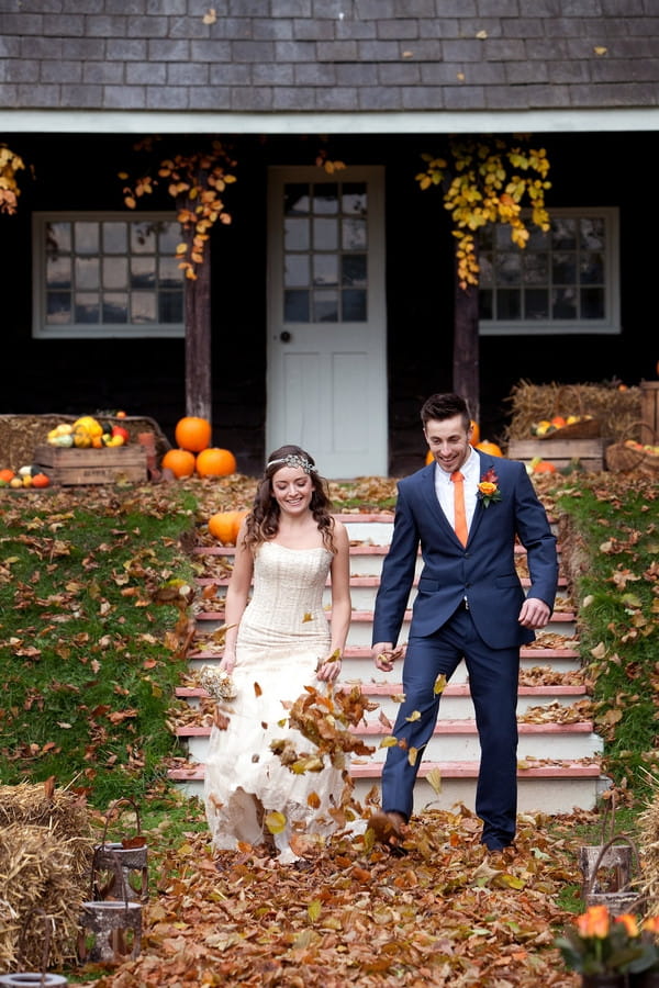 Bride and groom kicking autumn leaves