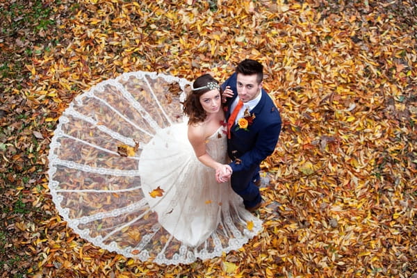 Bride and groom standing in autumn leaves