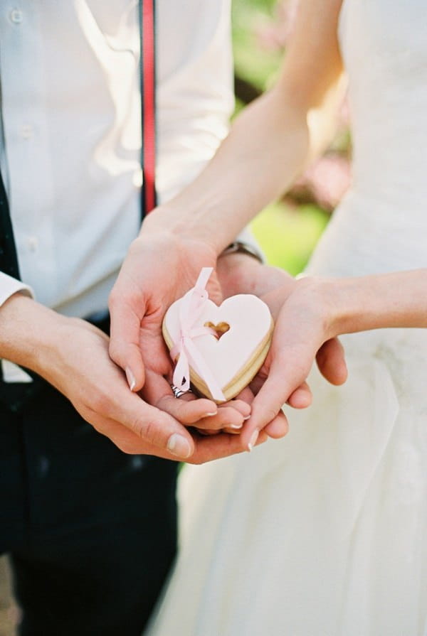 Bride and groom holding heart-shaped biscuit