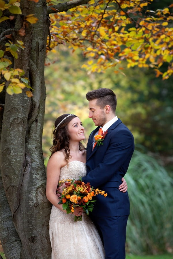 Bride and groom standing under tree in autumn