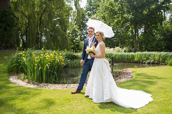 Bride and groom in front of pond in Houchins garden