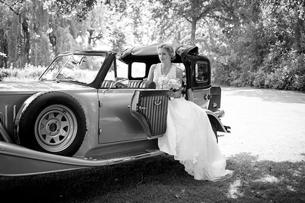 Bride sitting in vintage wedding car