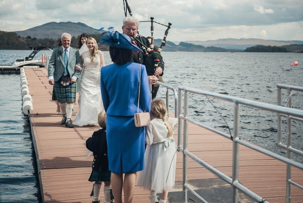 Bagpiper leading bride and father down jetty on Loch Lomond