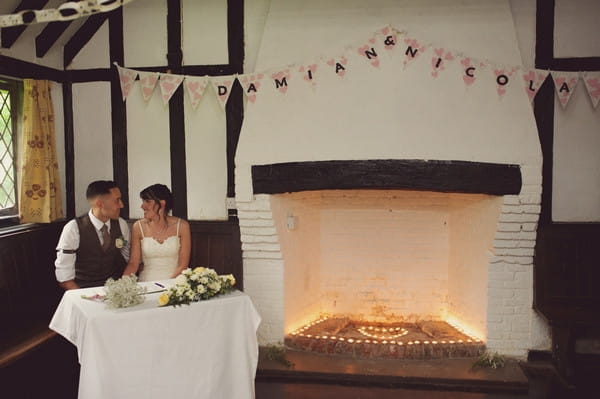 Bride and groom sitting by fireplace