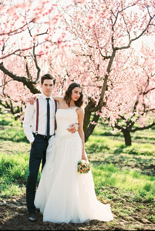 Bride and groom standing in front of blossom covered tree