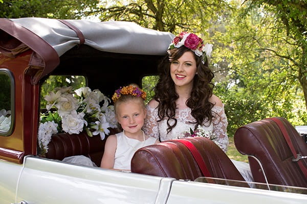 Bride and flower girl in back of wedding car