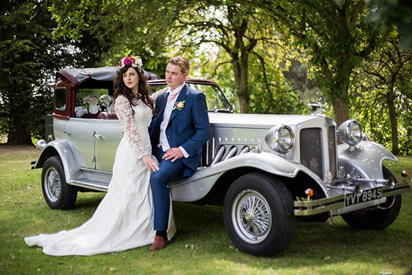 Bride and groom next to vintage wedding car