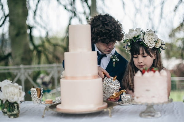 Young groomsman pouring tea for flower girl