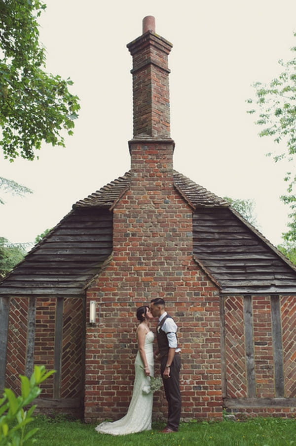 Bride and groom kissing by wall of Chilham Village Hall in Kent