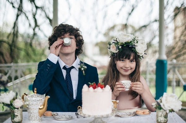 Young groomsman and flower girl drinking tea