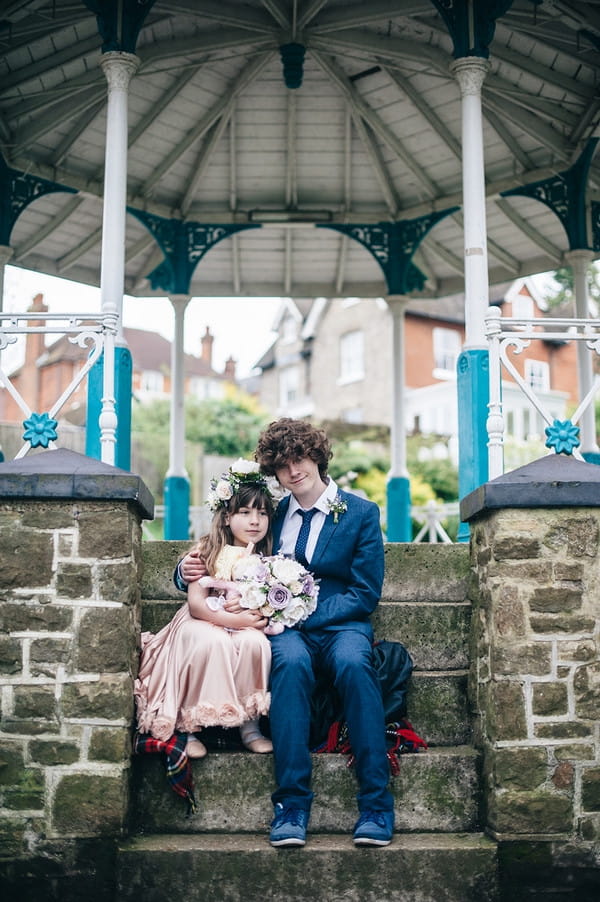 Young flower girl and groomsman sitting on steps of bandstand