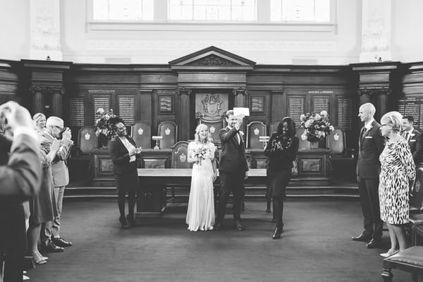 Groom holding up marriage certificate in Islington Town Hall
