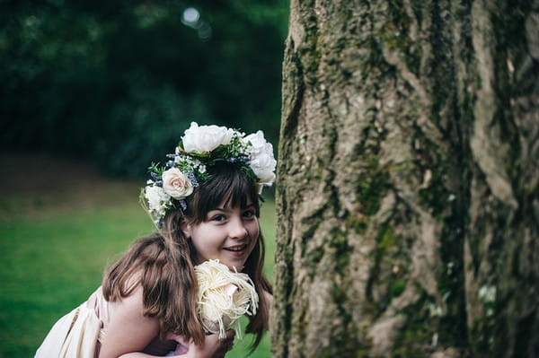 Young flower girl hiding behind tree