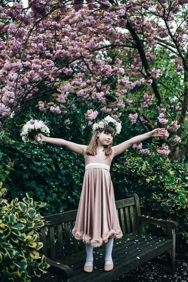 Flower girl standing on bench with arms out