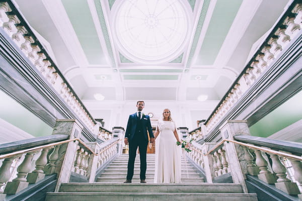 Bride and groom holding hands on steps in Islington Town Hall