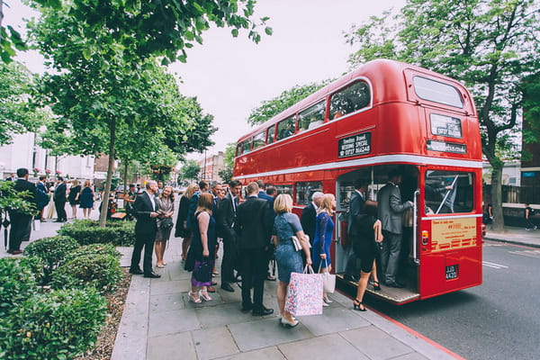 Wedding guests getting on to red wedding bus