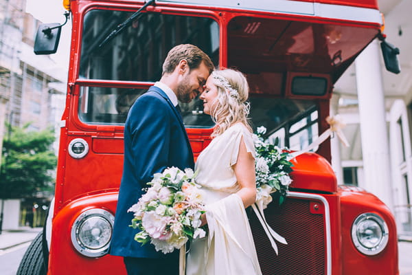 Bride and groom in front of red bus