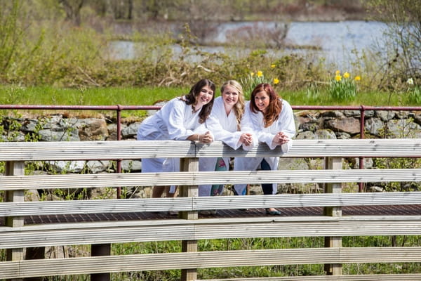 Bride and bridesmaids leaning on fence