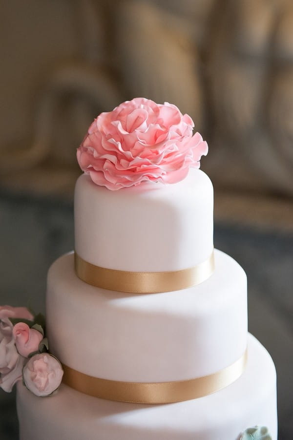 Pink flower on top of elegant wedding cake
