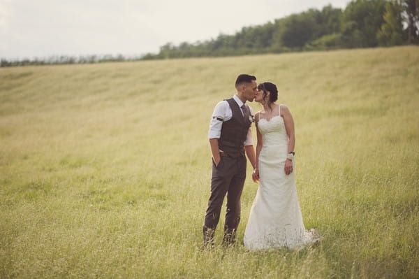 Bride and groom kissing in field