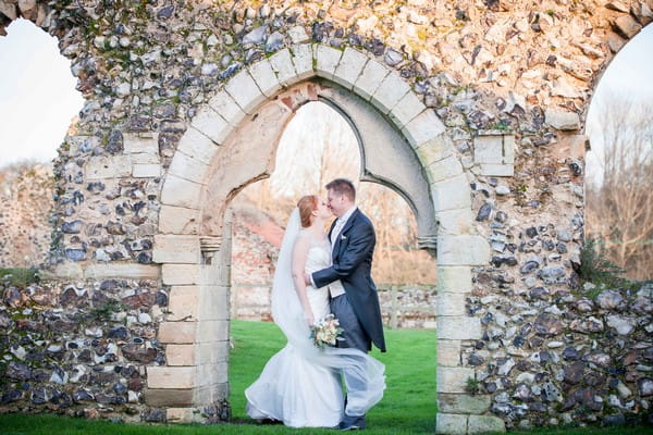 Bride and groom standing in opening in wall - Picture by Amanda Karen Photography