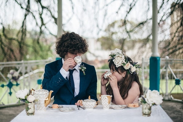 Young groomsman and flower girl drinking tea in park