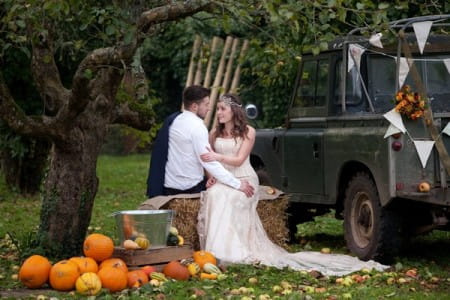 Bride and groom sitting by Land Rover in Derr Park at autumn
