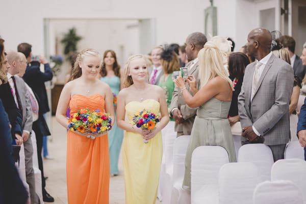 Bridesmaids walking down aisle in bright dresses