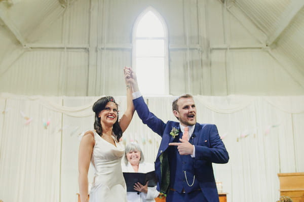 Groom holding bride's arm in air