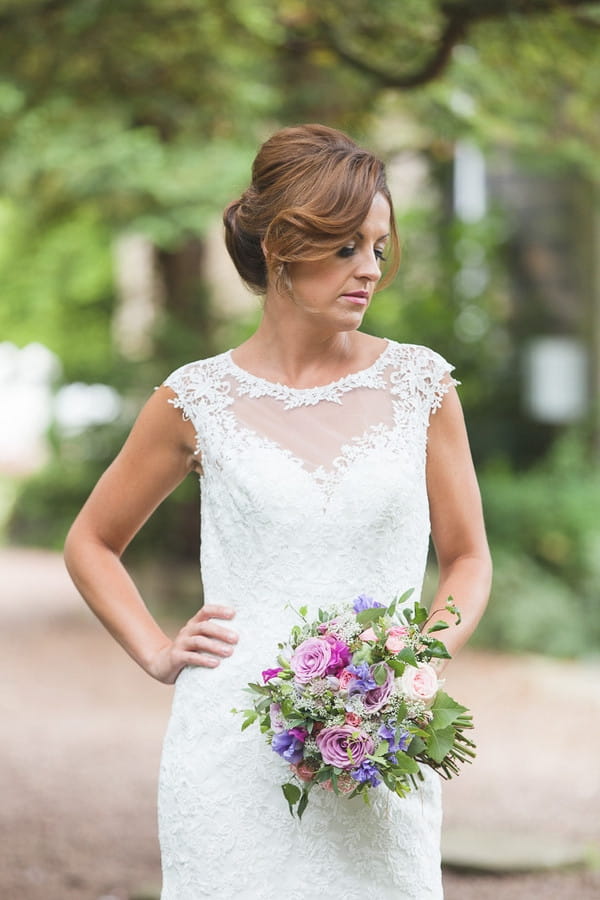 Bride with hand on hip holding bouquet