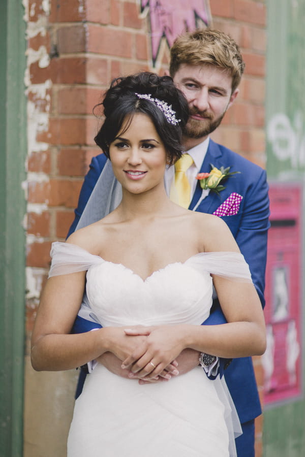 Groom behind bride with hands around her waist