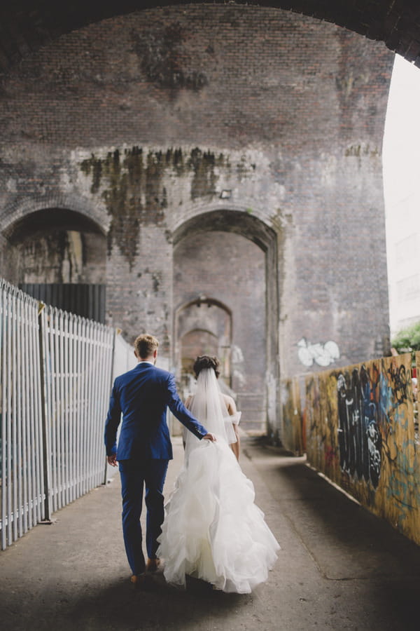 Bride and groom walking past graffiti wall in Birmingham