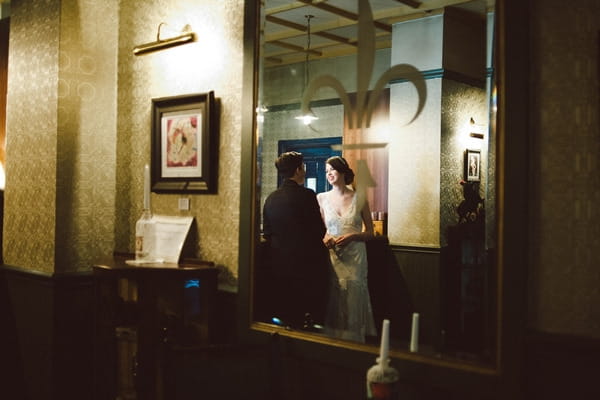 Reflection of bride and groom in bar mirror