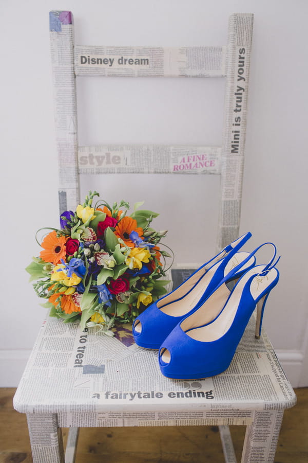 Blue wedding shoes in chair with colourful bouquet