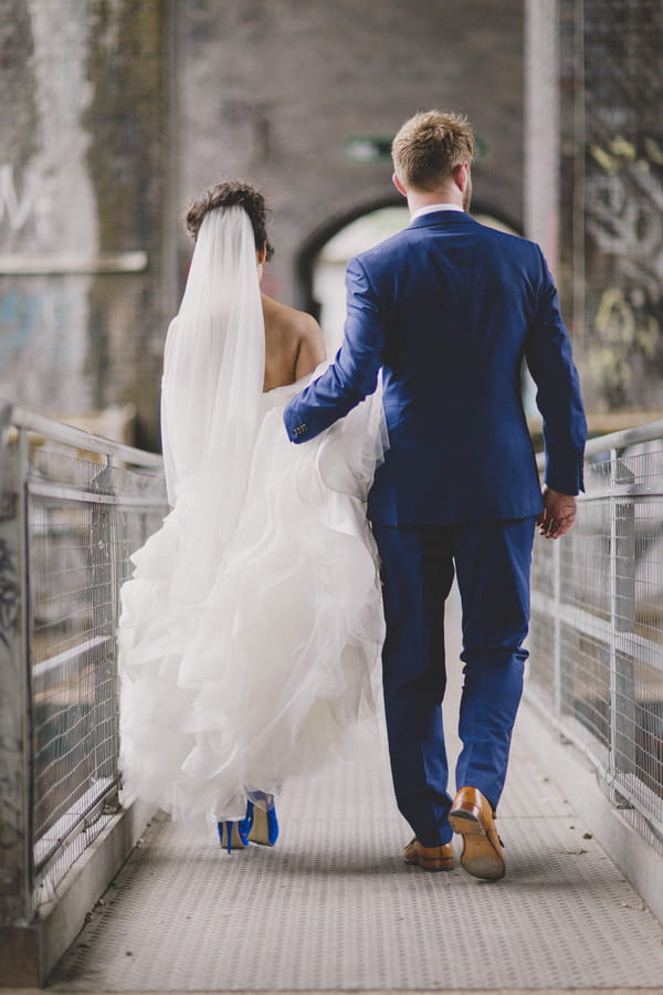 Groom holding up bride's dress as she walks