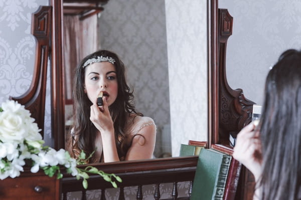 Retro bride doing lipstick in mirror