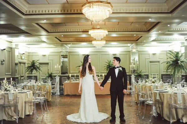 Bride and groom holding hands in ballroom