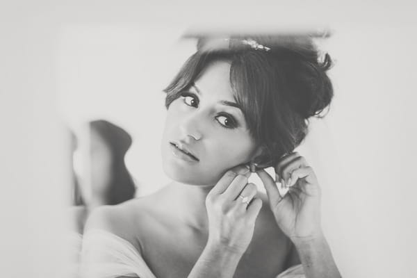 Bride putting on earrings