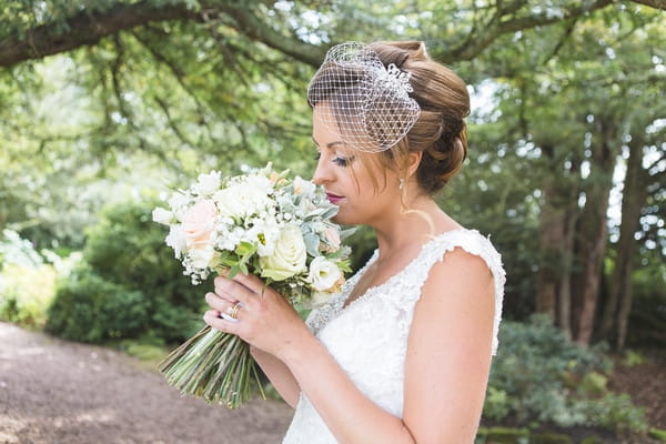 Bride with birdcage veil smelling bouquet