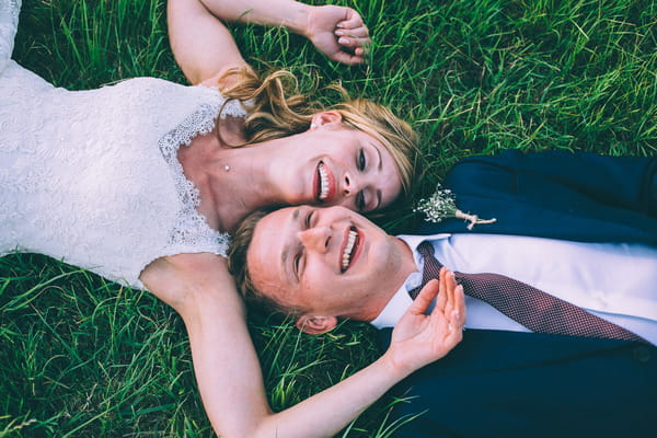 Bride and groom laying on grass