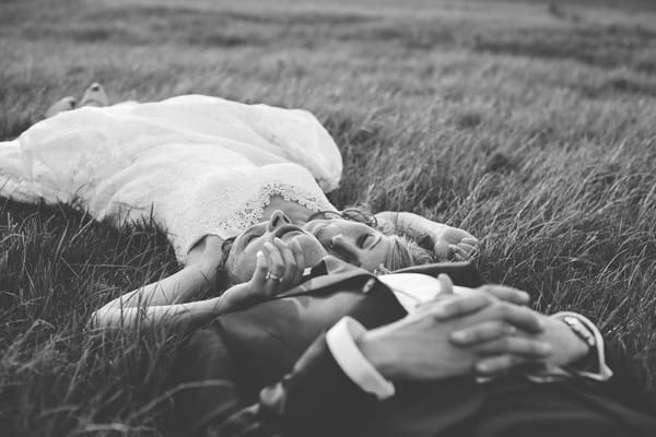 Bride and groom laying on grass
