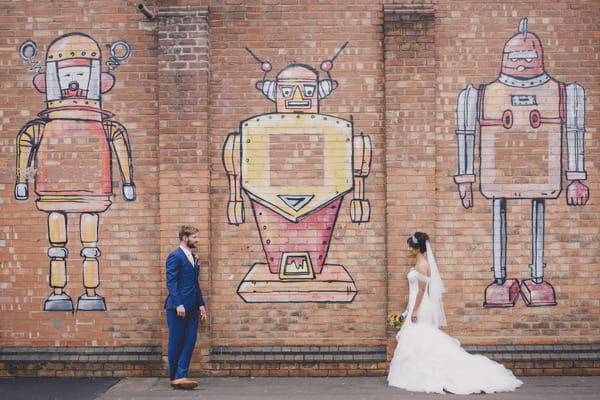 Bride and groom in front of graffiti wall with robots, in Birmingham