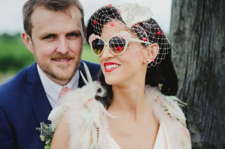Groom with bride wearing birdcage veil and sunglasses