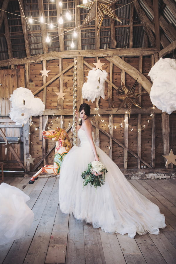 Bride holding bouquet sitting on carousel horse