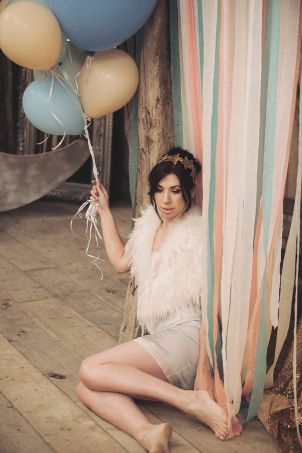 Bride sitting on floor holding balloons