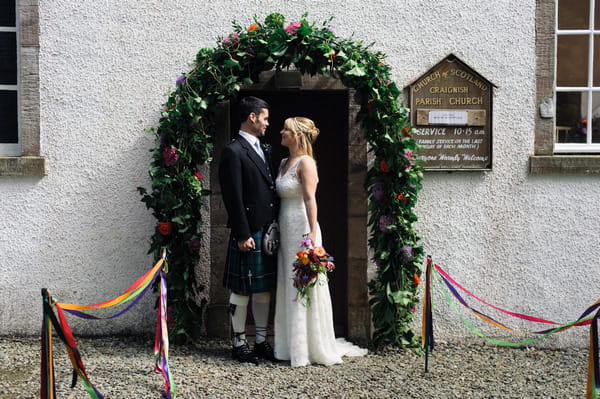 Bride and groom in front of entrance to Church of Scotland, Ardfern